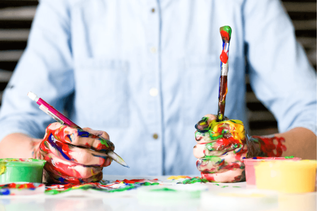 Man with paintbrush and pencil with paint on his hands